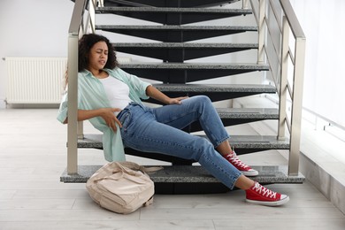 Photo of Woman with injured back on stairs in building after fall. Dangerous accident