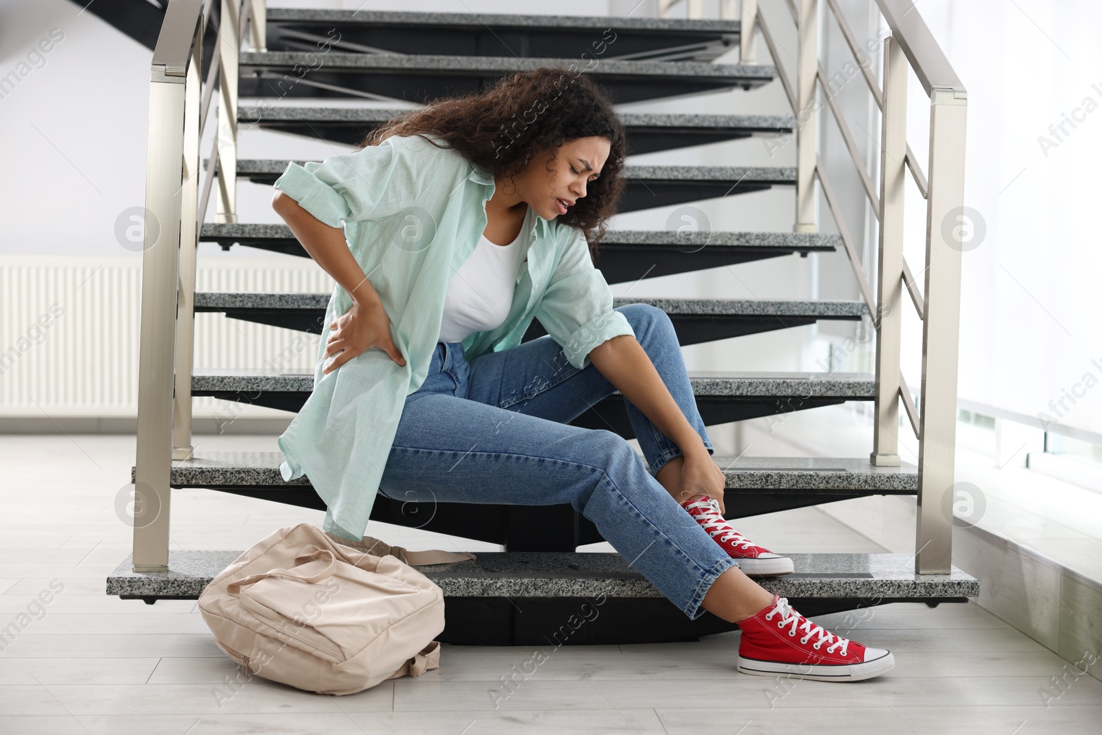 Photo of Woman with injured back on stairs in building after fall. Dangerous accident