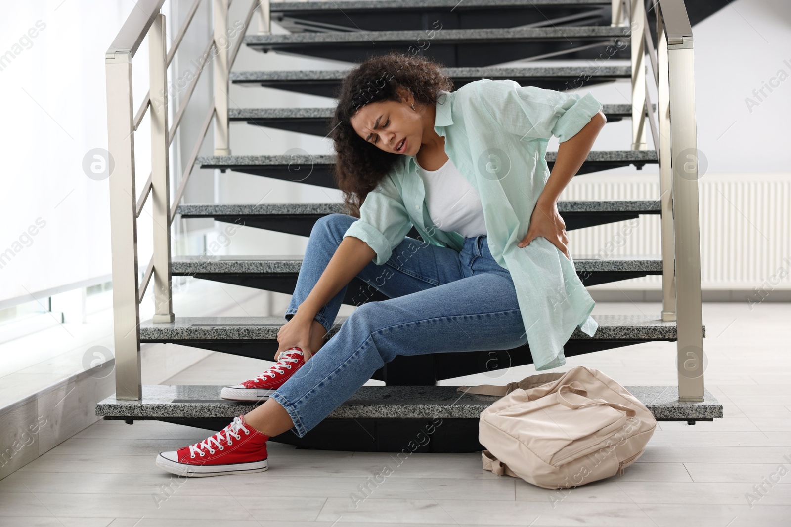 Photo of Woman with injured back on stairs in building after fall. Dangerous accident