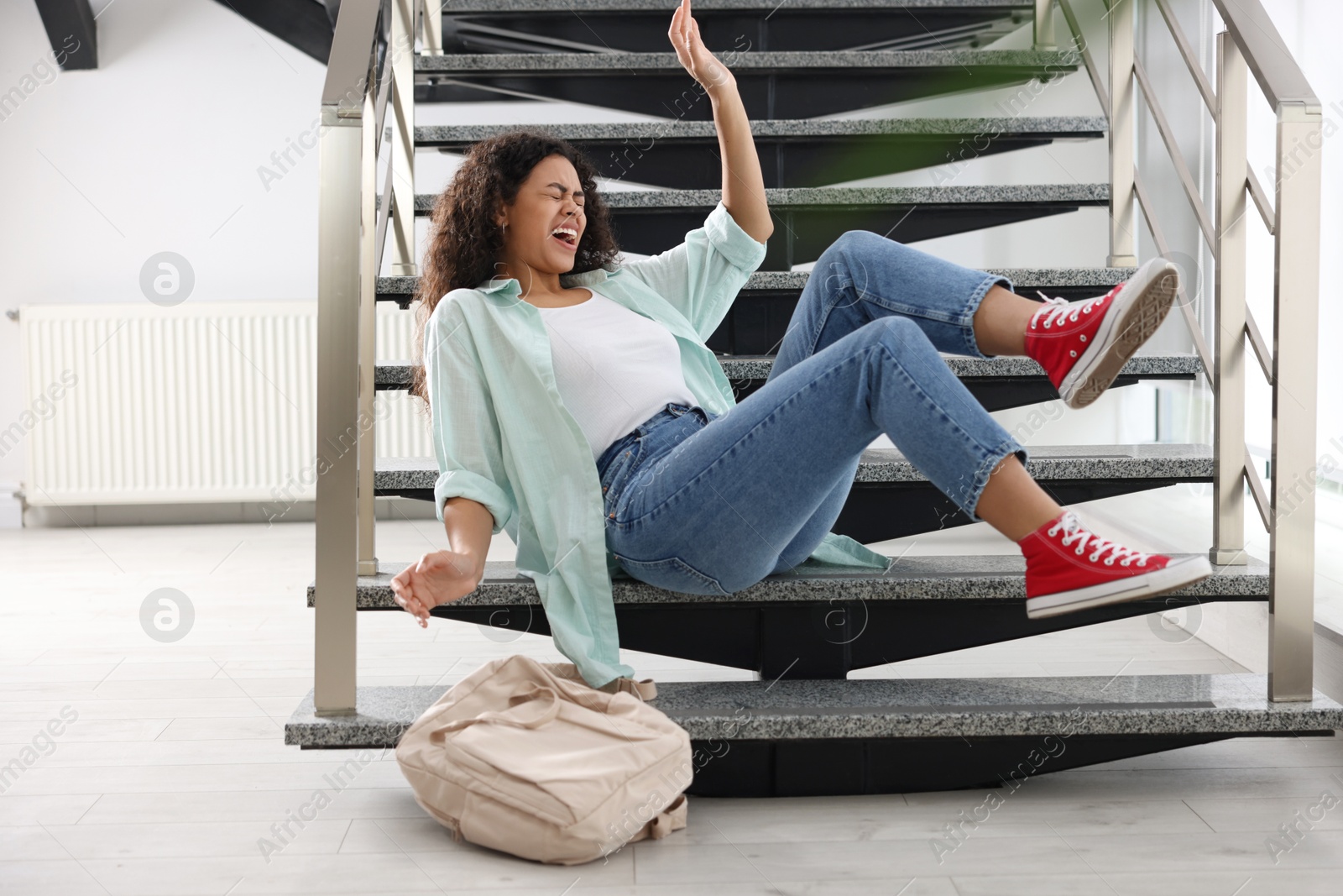 Photo of Injured woman on stairs in building after fall. Dangerous accident