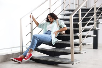 Photo of Woman with injured back on stairs in building after fall. Dangerous accident