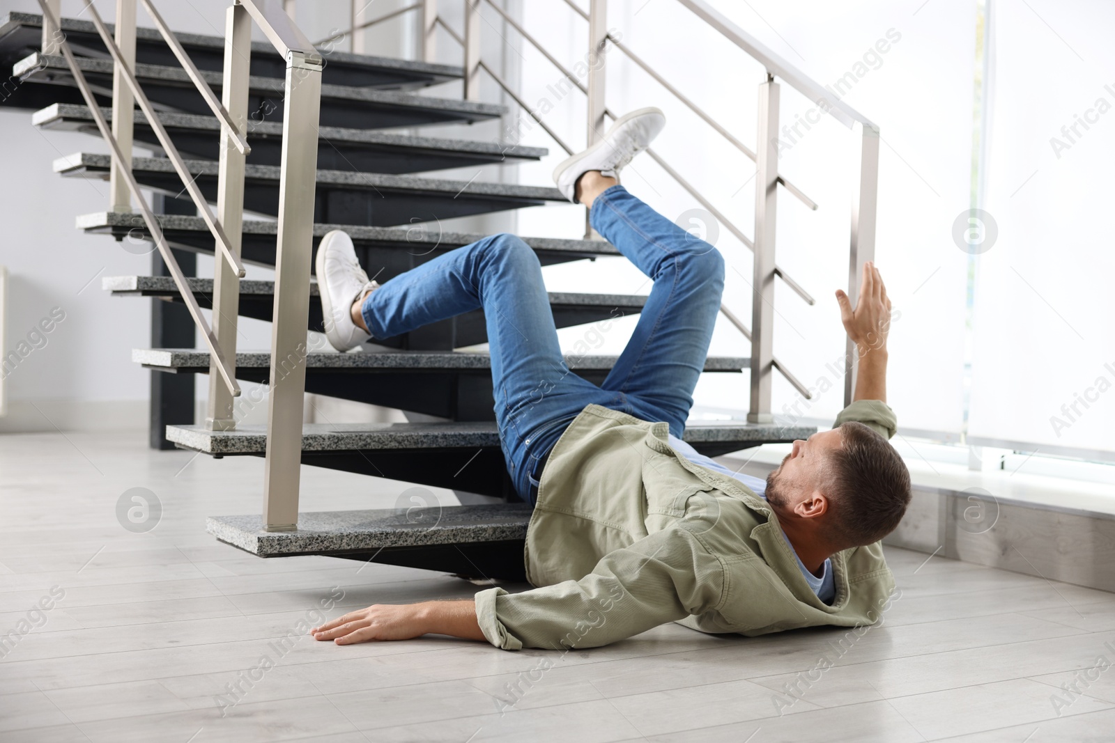 Photo of Injured man on floor in building after fall from stairs. Dangerous accident