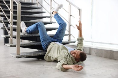 Photo of Injured man on floor in building after fall from stairs. Dangerous accident