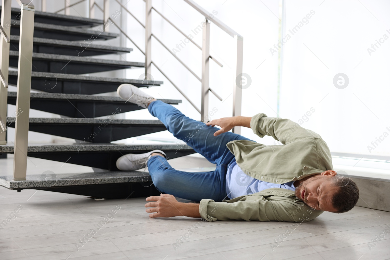 Photo of Injured man on floor in building after fall from stairs. Dangerous accident