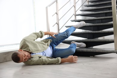 Photo of Injured man on floor in building after fall from stairs. Dangerous accident