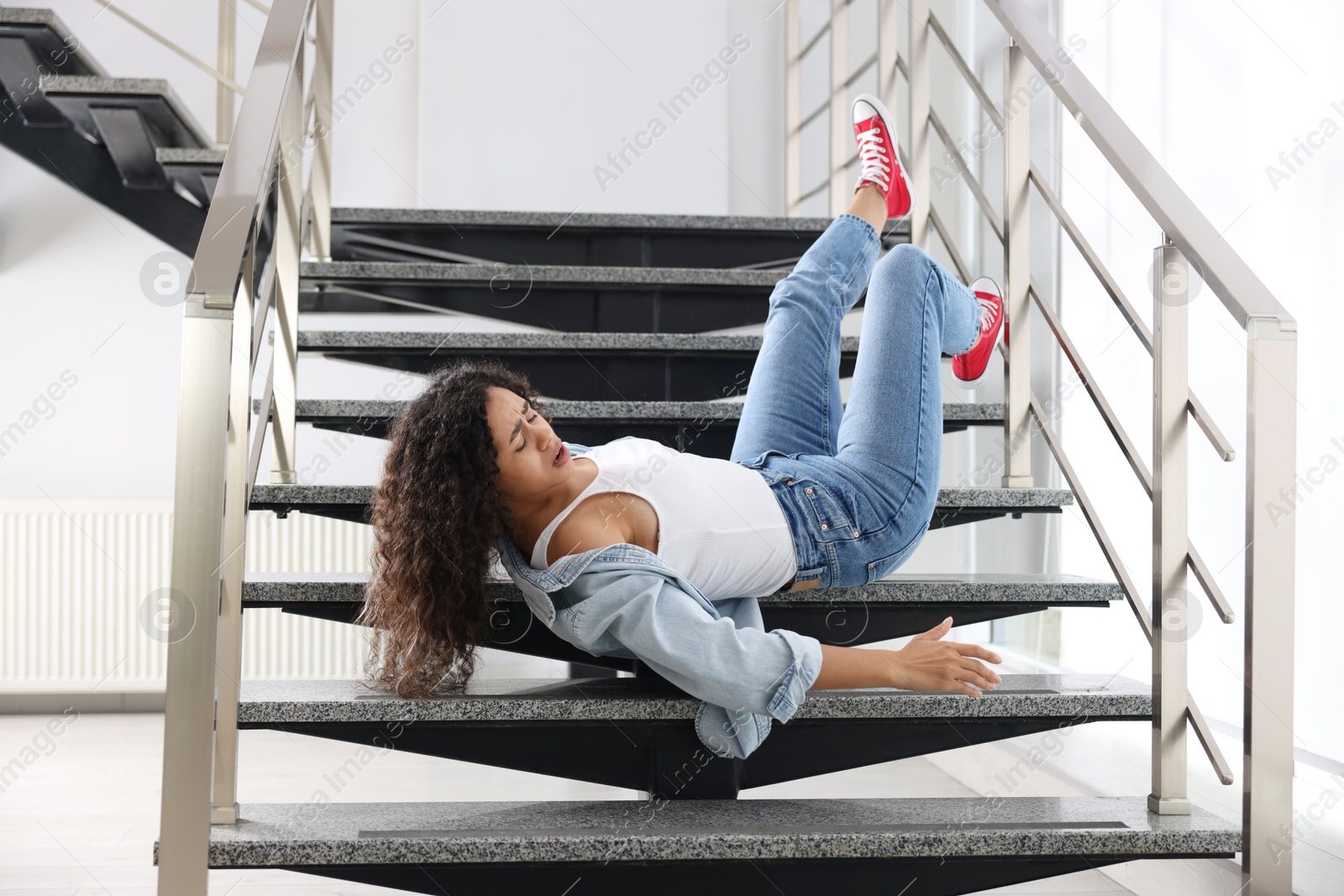 Photo of Injured woman on stairs in building after fall. Dangerous accident