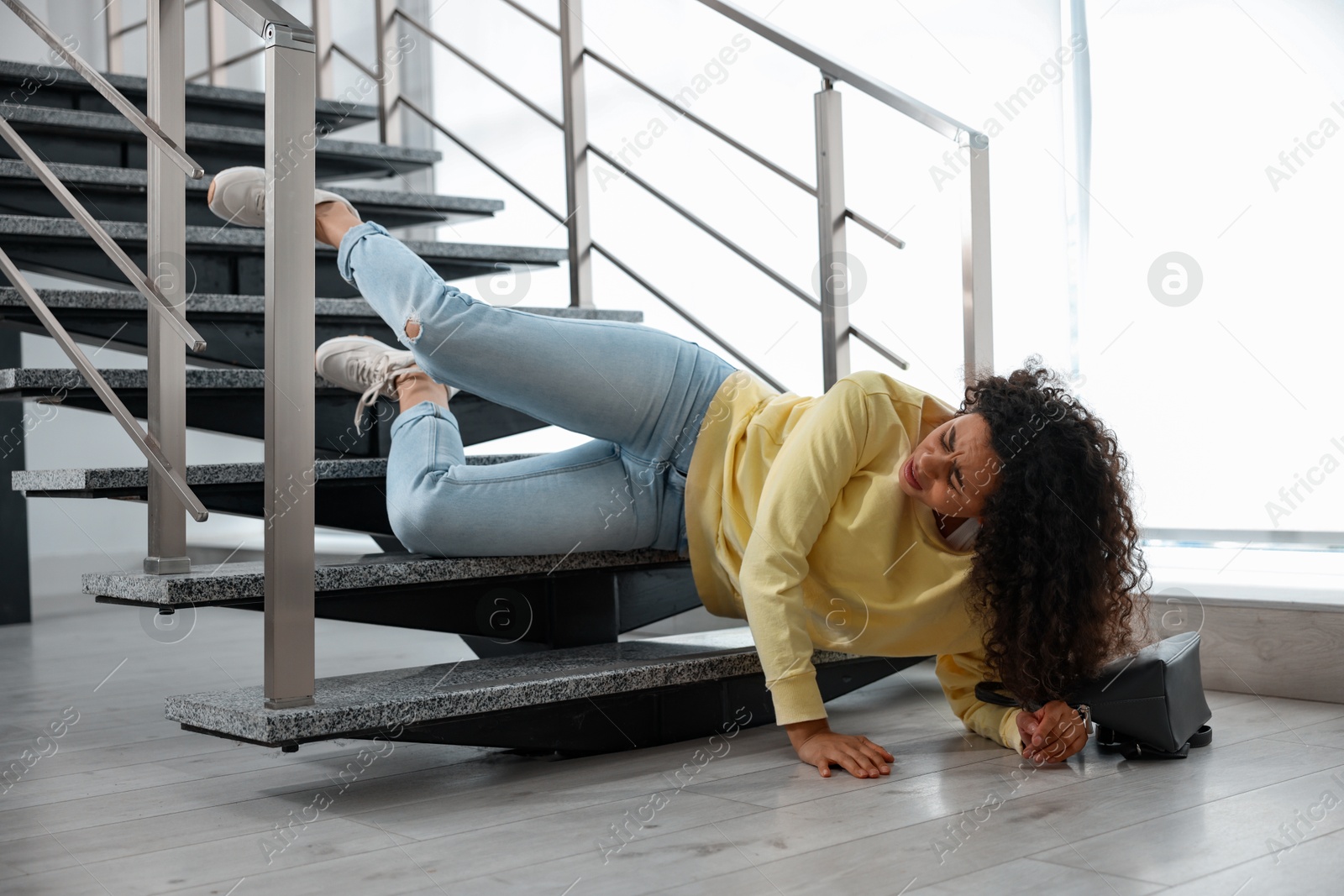 Photo of Injured woman on stairs in building after fall. Dangerous accident