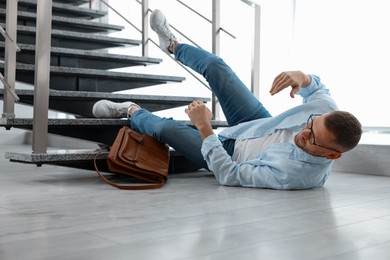 Photo of Injured man on floor in building after fall from stairs. Dangerous accident