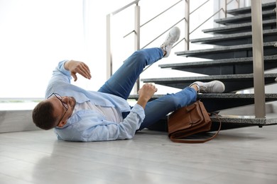 Photo of Injured man on floor in building after fall from stairs. Dangerous accident