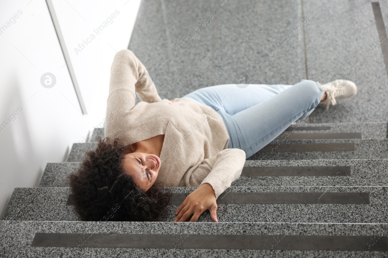 Photo of Injured woman on stairs in building after fall, above view. Dangerous accident