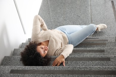 Photo of Injured woman on stairs in building after fall, above view. Dangerous accident