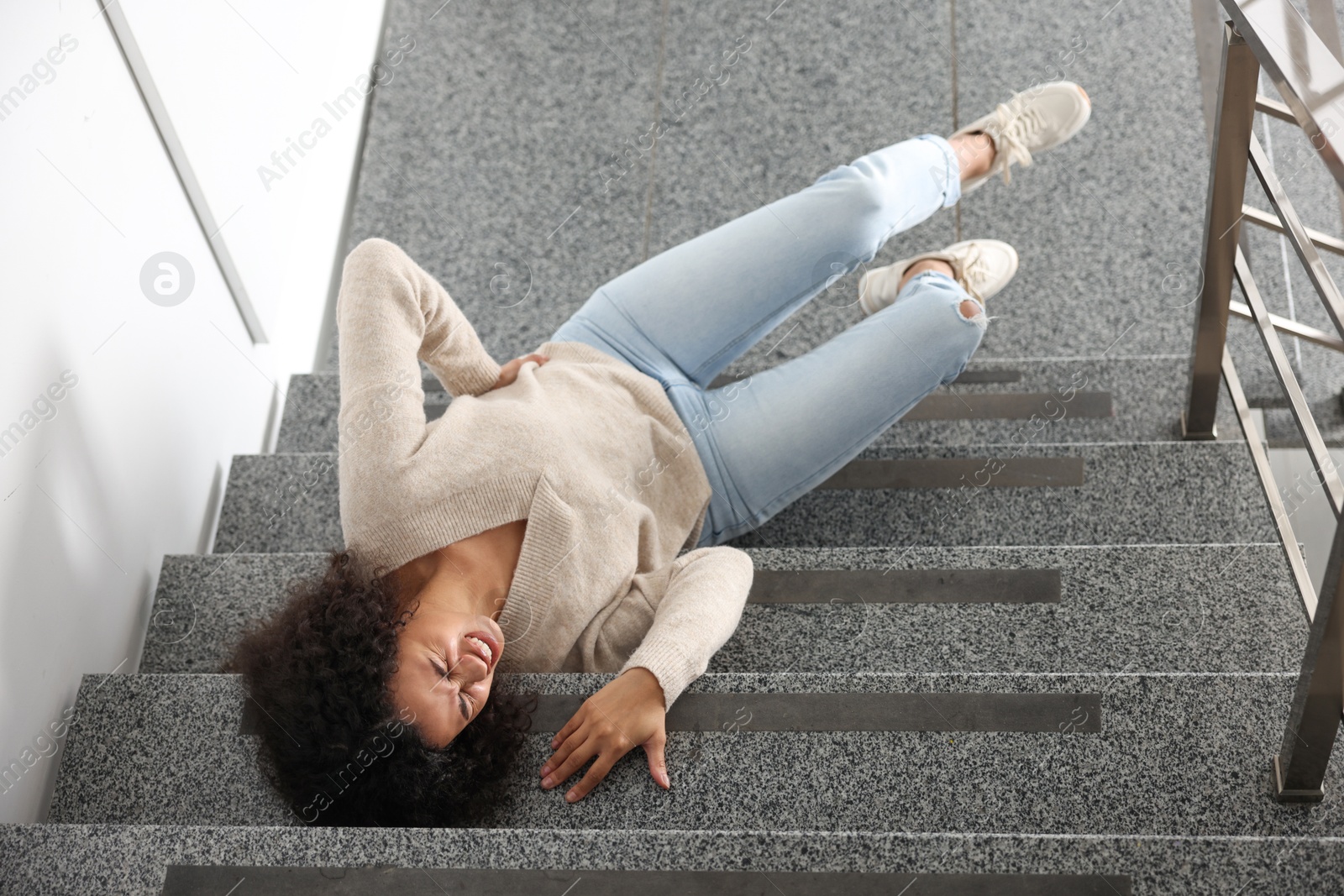 Photo of Injured woman on stairs in building after fall, above view. Dangerous accident