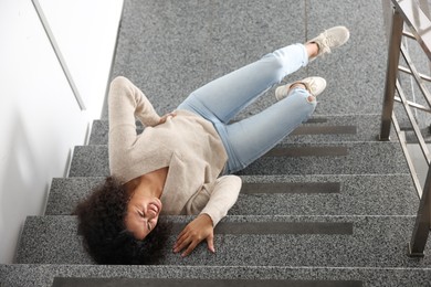 Photo of Injured woman on stairs in building after fall, above view. Dangerous accident