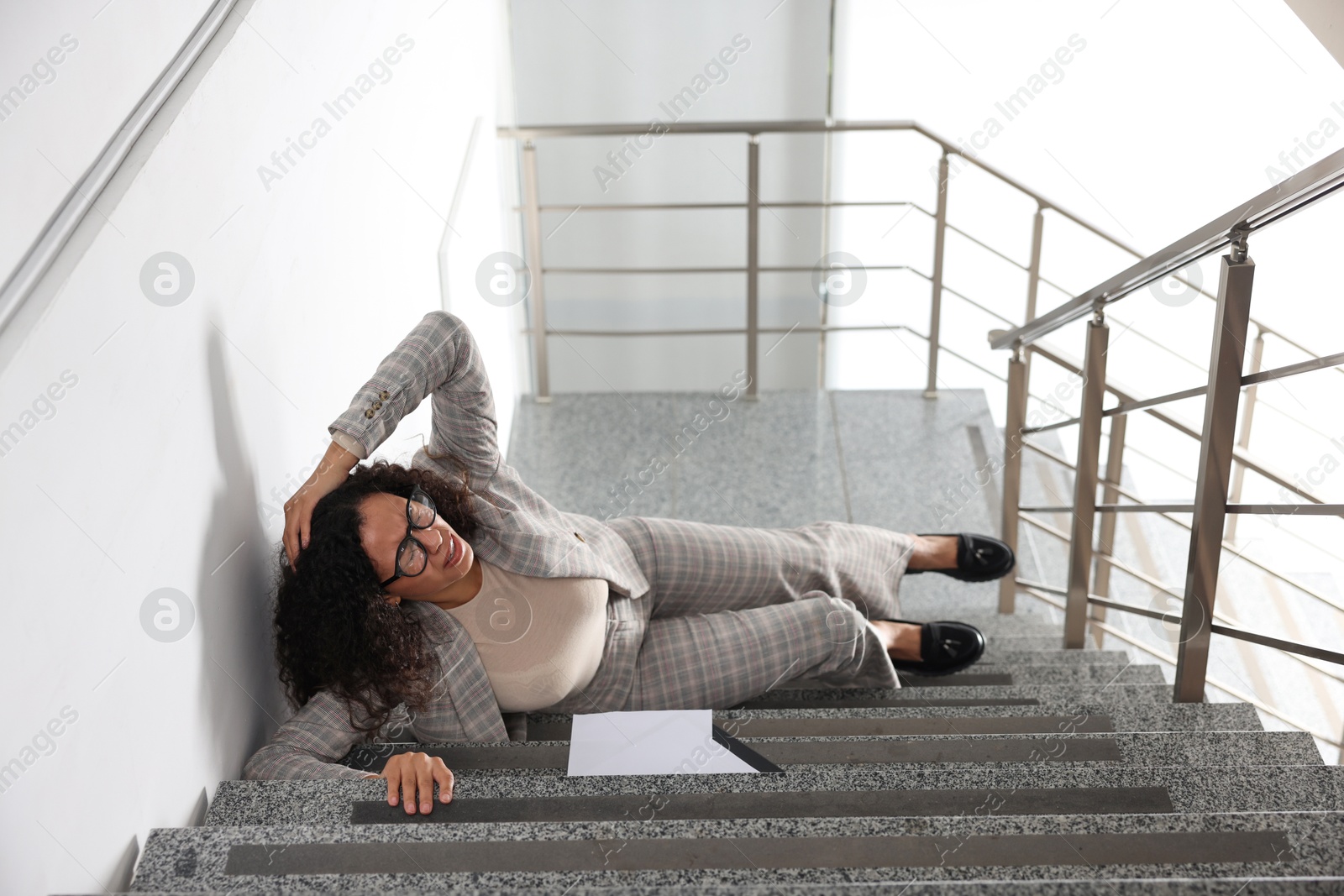 Photo of Woman with injured head on stairs in building after fall. Dangerous accident