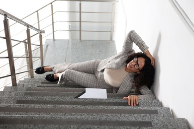 Photo of Woman with injured head on stairs in building after fall. Dangerous accident