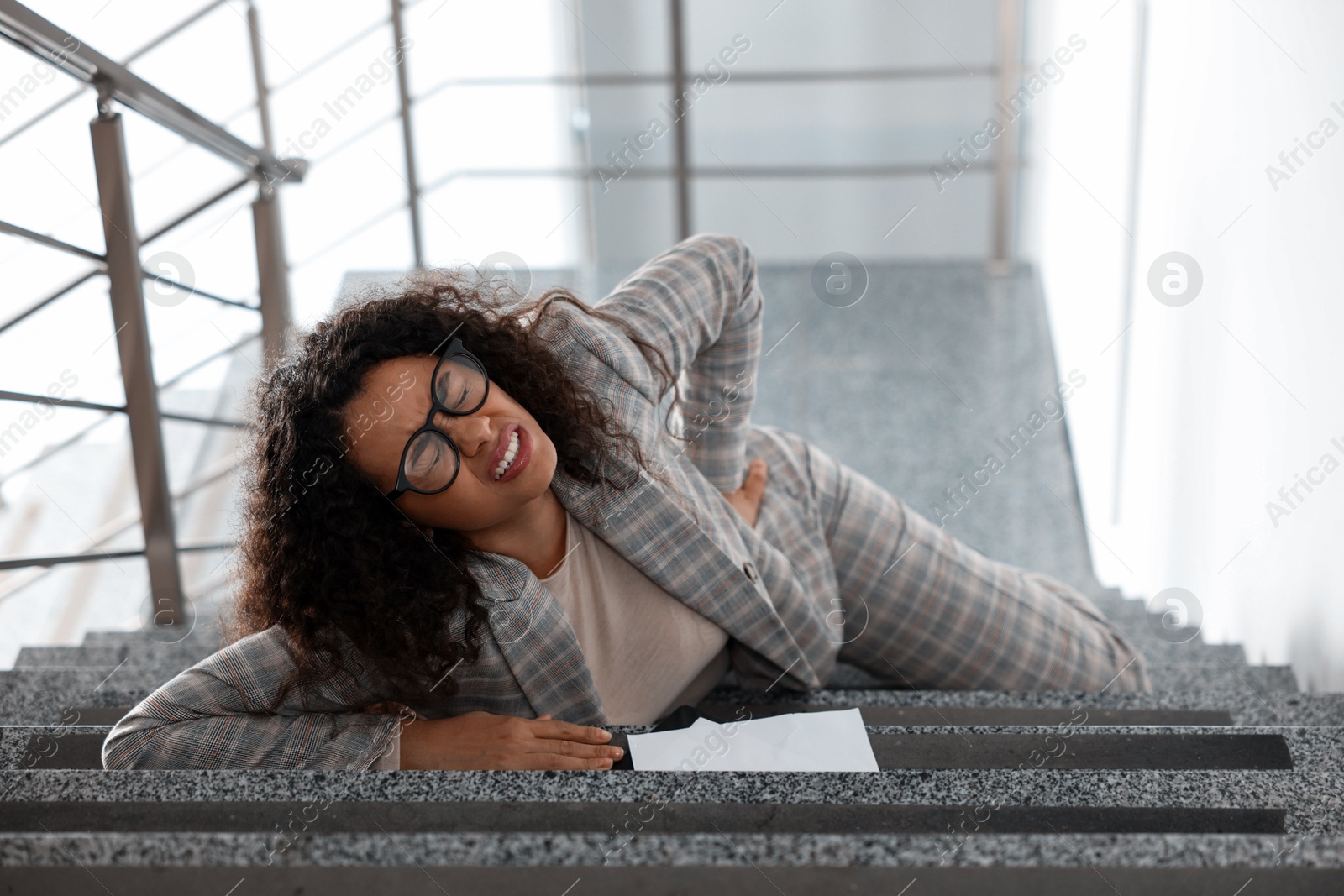 Photo of Injured woman on stairs in building after fall. Dangerous accident