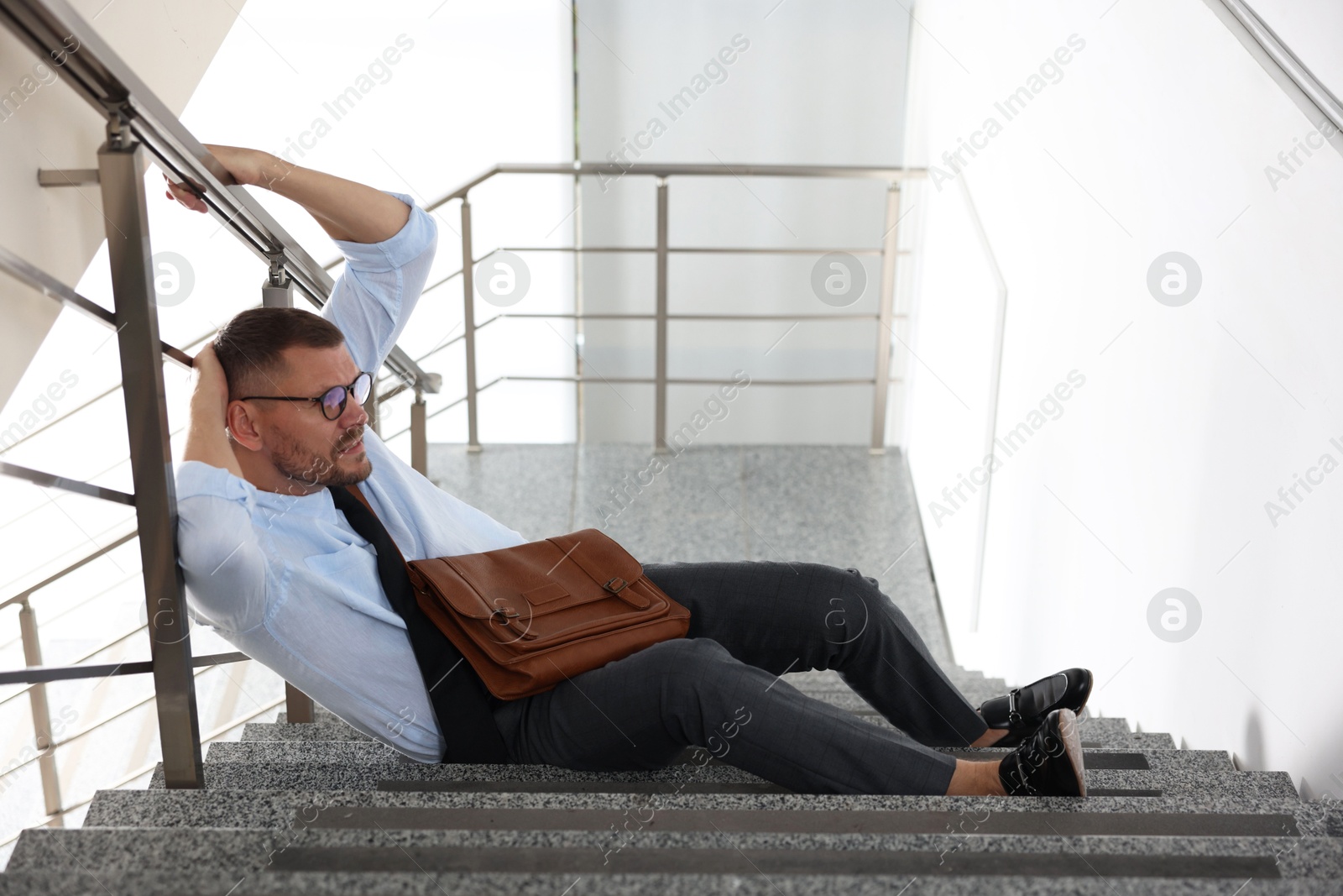 Photo of Man with injured head on stairs in building after fall. Dangerous accident