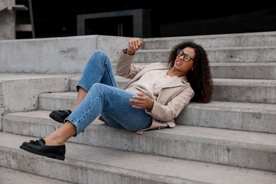 Photo of Injured woman on stairs outdoors after fall. Dangerous accident