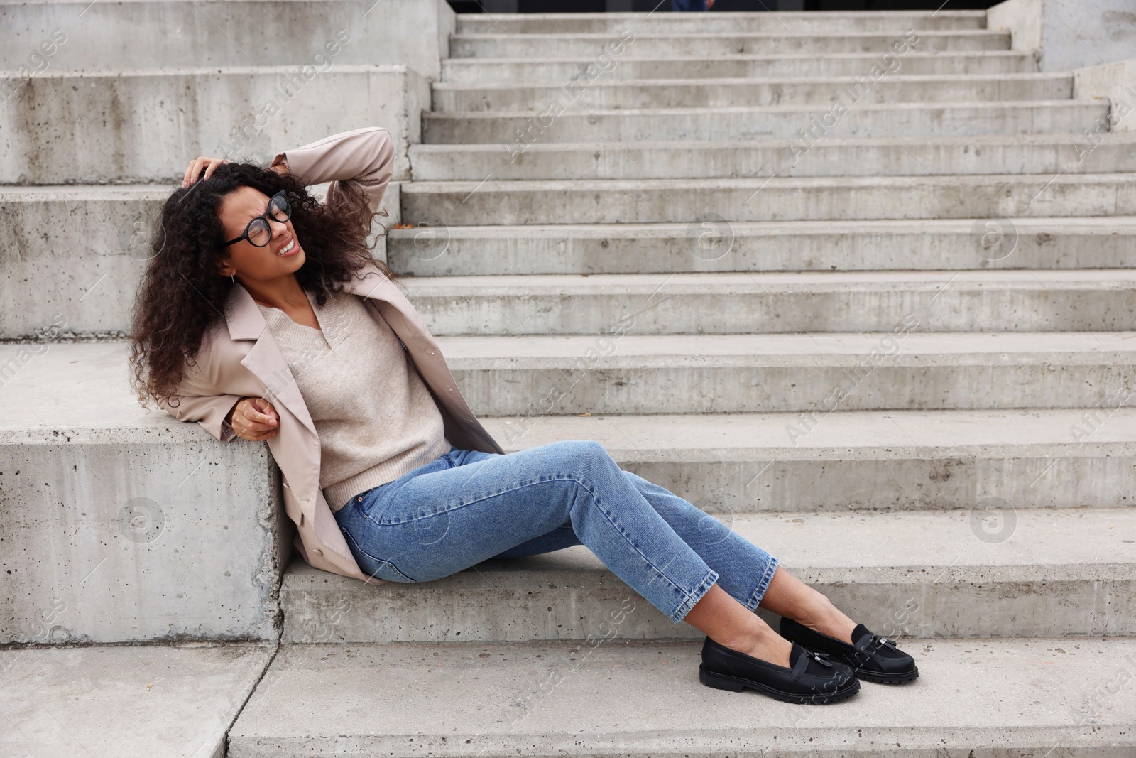 Photo of Woman with injured head on stairs outdoors after fall. Dangerous accident