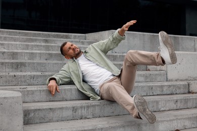 Photo of Man falling on stairs outdoors. Dangerous accident