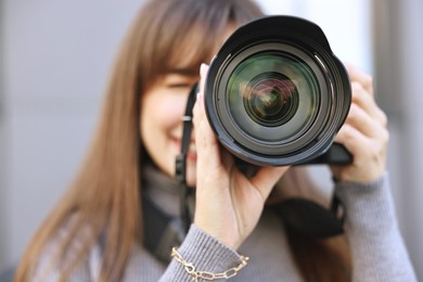 Photo of Professional photographer taking picture with camera outdoors, selective focus