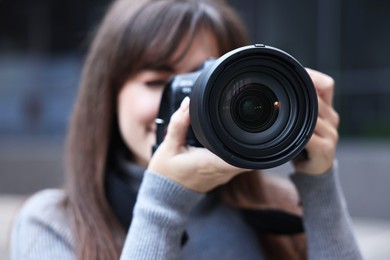 Photo of Professional photographer taking picture with camera outdoors, selective focus