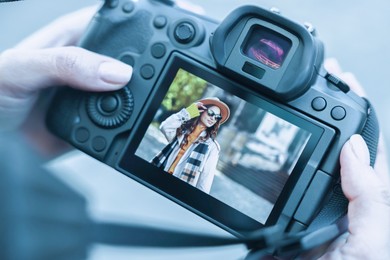 Photo of Professional photographer with digital camera outdoors, closeup