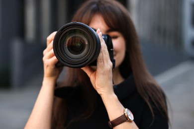 Photo of Professional photographer taking picture with camera outdoors, selective focus