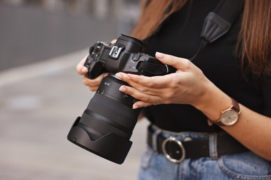 Photo of Professional photographer with digital camera outdoors, closeup