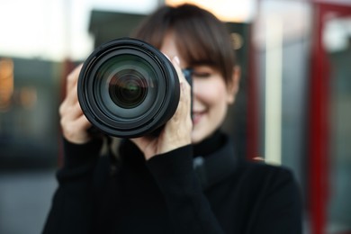 Photo of Professional photographer taking picture with camera outdoors, selective focus