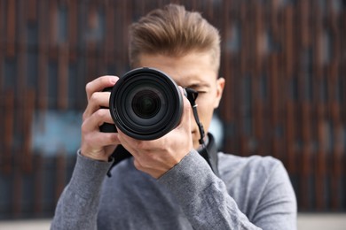 Photo of Professional photographer taking picture with camera outdoors, selective focus