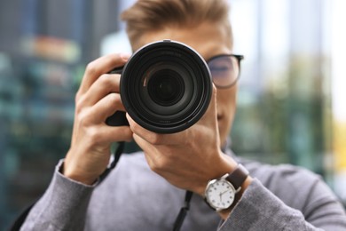 Photo of Professional photographer taking picture with camera outdoors, selective focus