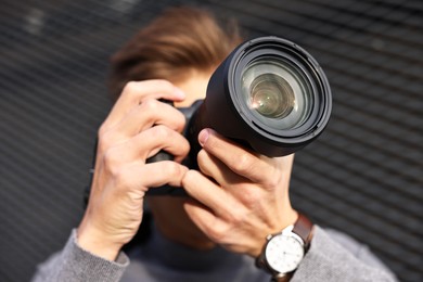 Photo of Professional photographer taking picture with camera outdoors, selective focus