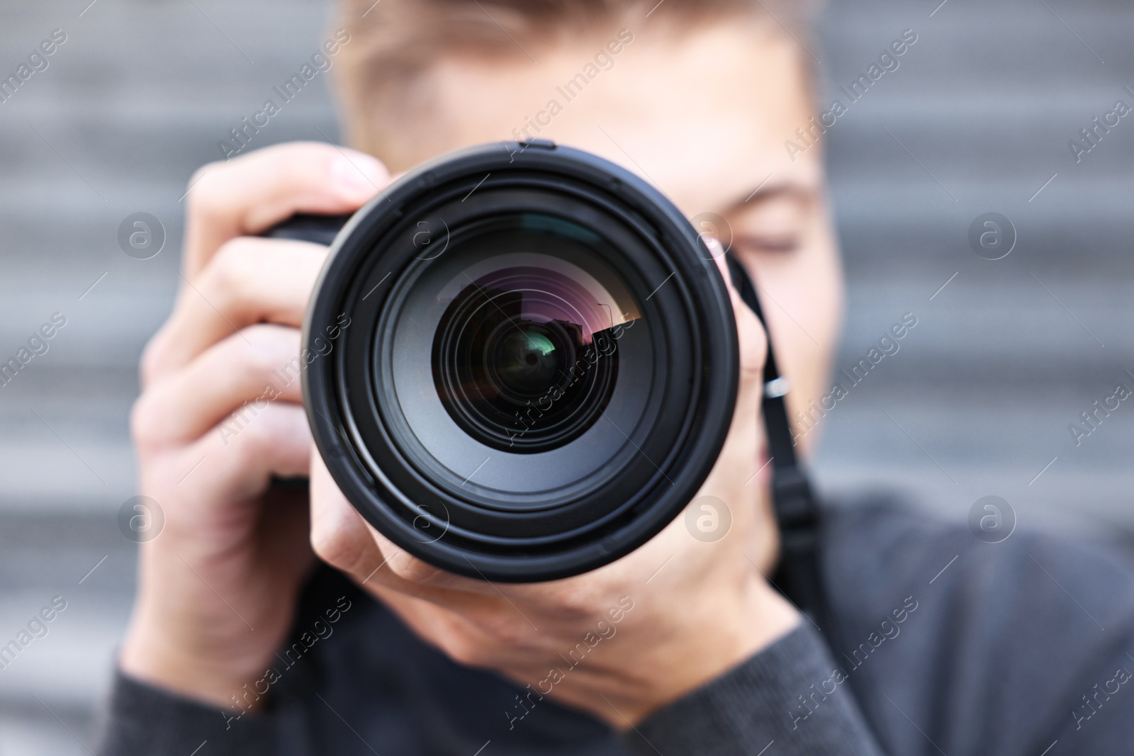 Photo of Professional photographer taking picture with camera outdoors, selective focus