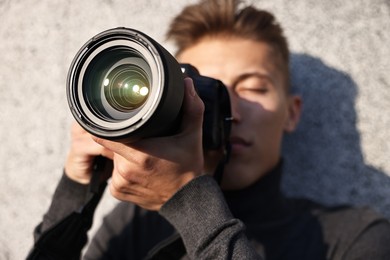 Photo of Professional photographer taking picture with camera outdoors, selective focus