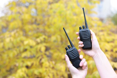 Photo of Woman with walkie talkies outdoors, closeup. Space for text