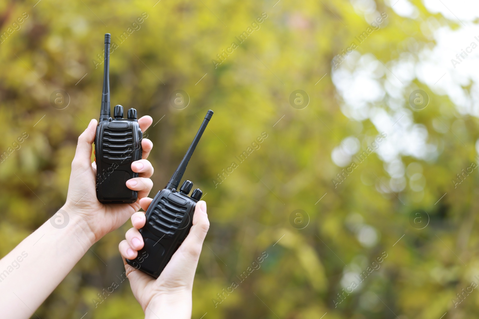 Photo of Woman with walkie talkies outdoors, closeup. Space for text