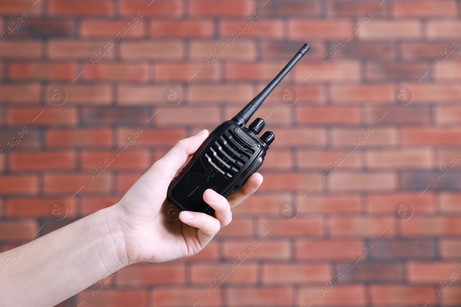 Photo of Woman with walkie talkie against brick wall, closeup