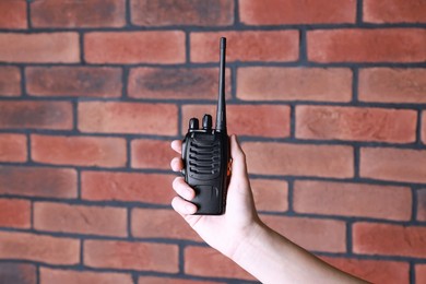 Photo of Woman with walkie talkie against brick wall, closeup