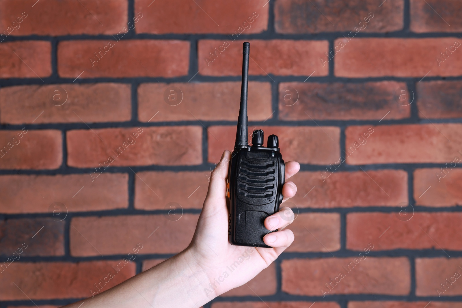 Photo of Woman with walkie talkie against brick wall, closeup