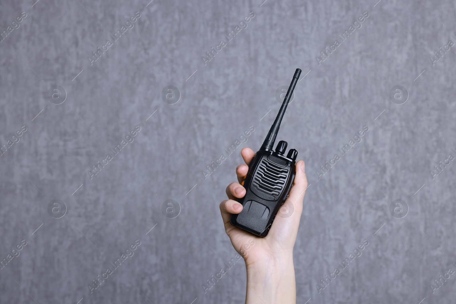 Photo of Woman with walkie talkie against grey background, closeup. Space for text