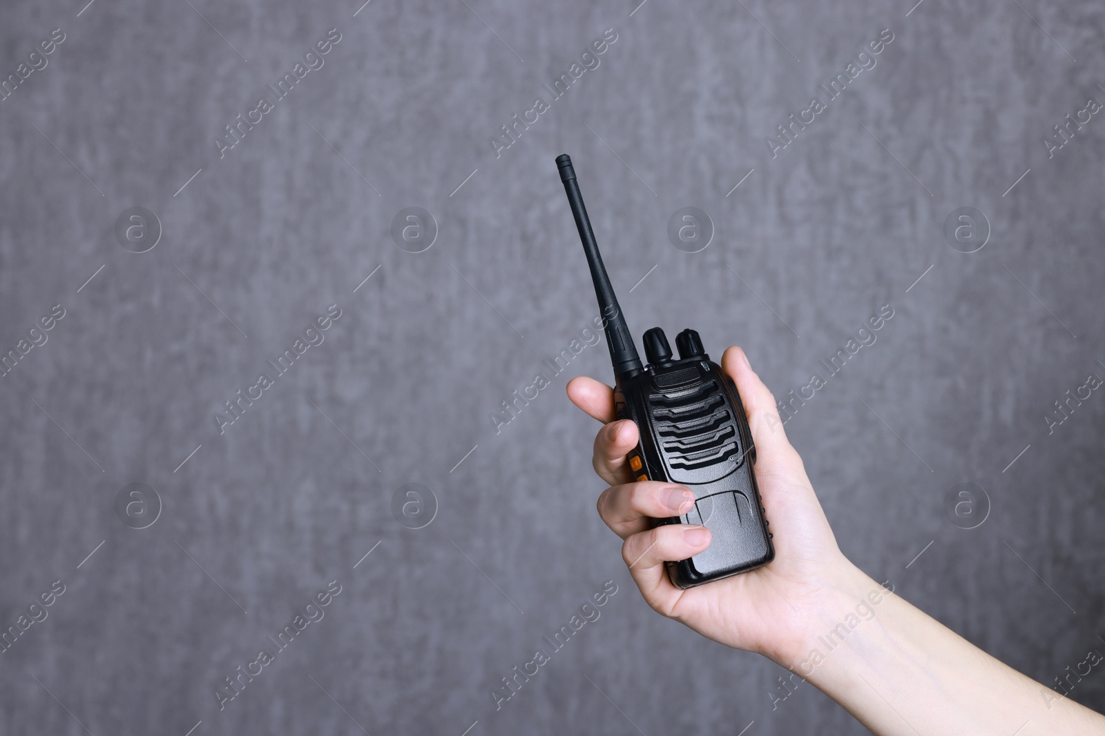 Photo of Woman with walkie talkie against grey background, closeup. Space for text