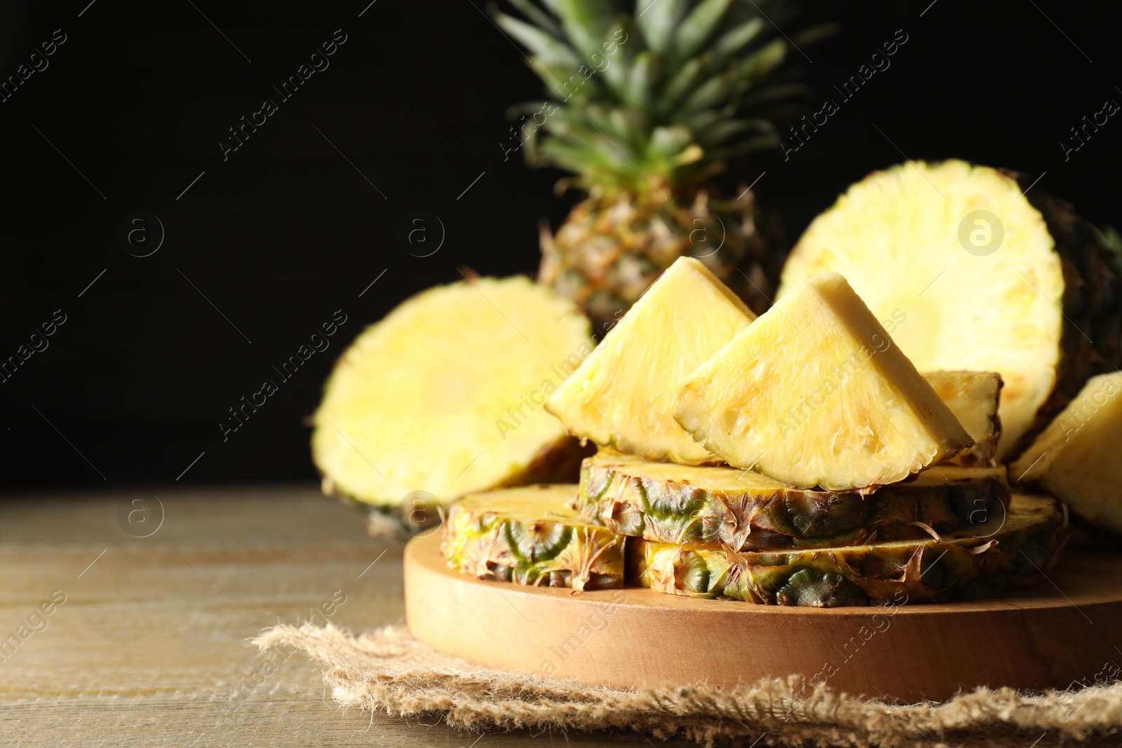 Photo of Slices of ripe pineapple on wooden table, closeup. Space for text