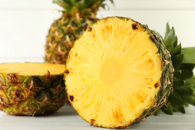 Photo of Cut fresh ripe pineapple on white wooden table, closeup