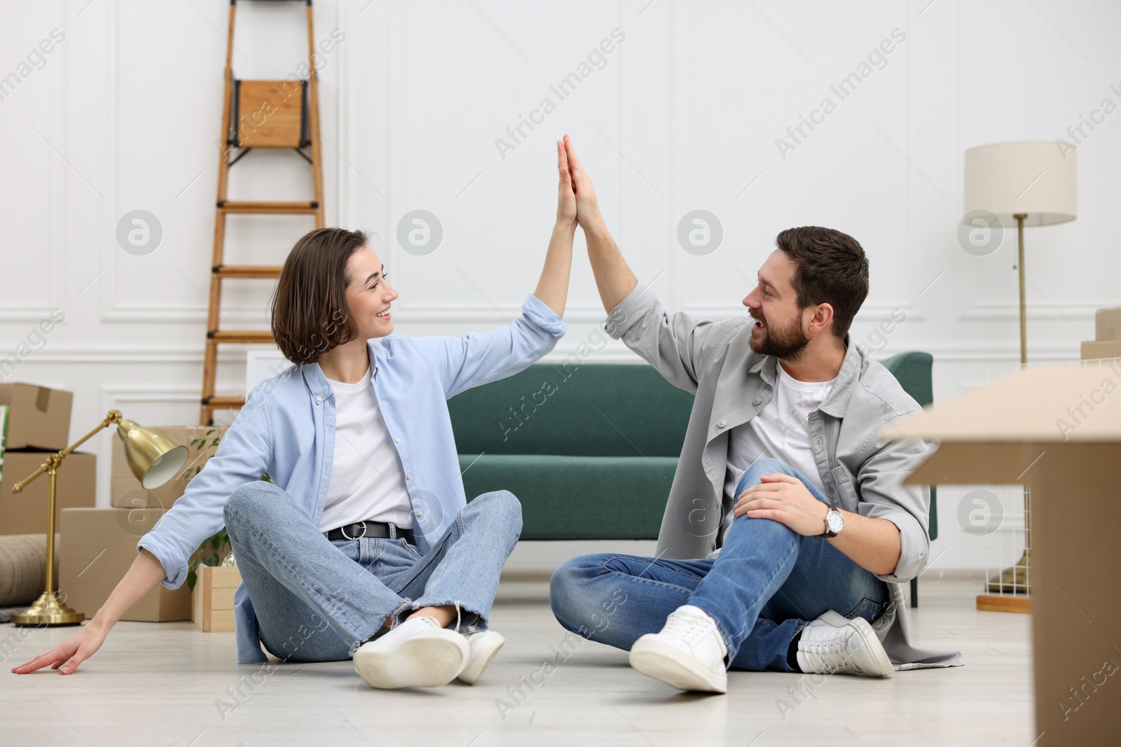 Photo of Moving day. Happy couple giving each other high five in their new home