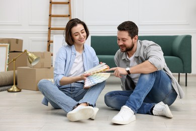 Photo of Moving day. Happy couple choosing paint color for their new home