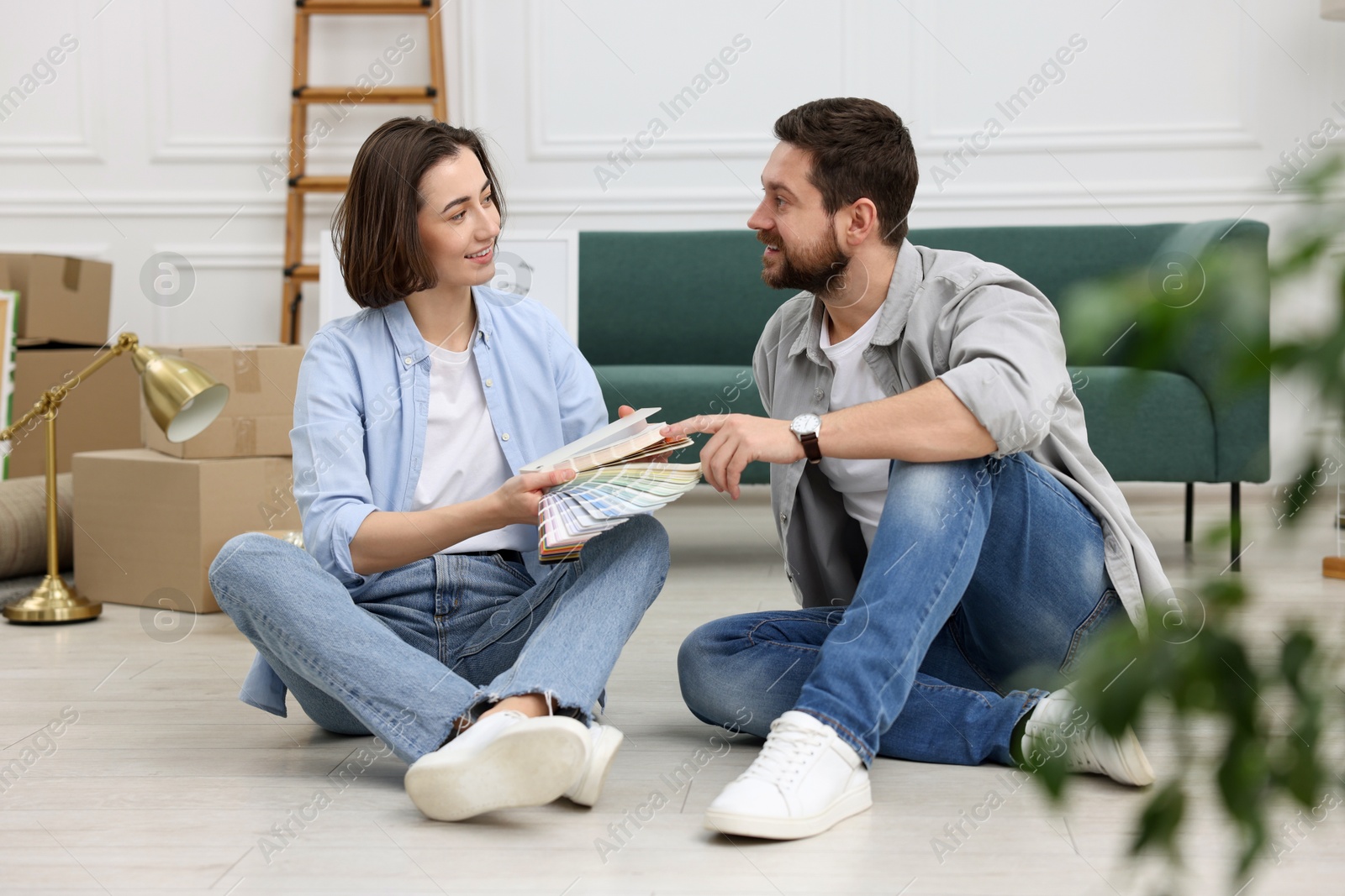 Photo of Moving day. Happy couple choosing paint color for their new home