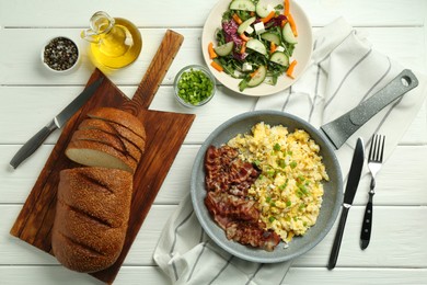 Photo of Tasty brunch. Delicious scrambled eggs, bacon and salad served on white wooden table, flat lay