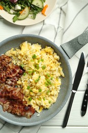 Photo of Tasty brunch. Delicious scrambled eggs, bacon and salad served on white wooden table, flat lay