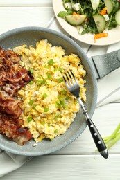 Photo of Tasty brunch. Delicious scrambled eggs, bacon and salad served on white wooden table, flat lay